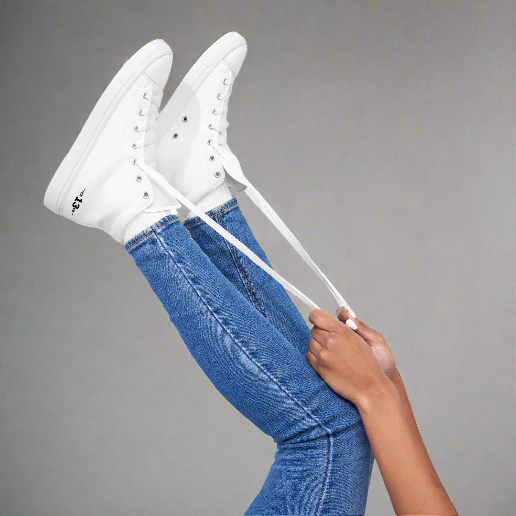 Woman wearing White High Top Canvas Shoes with legs upp in the air